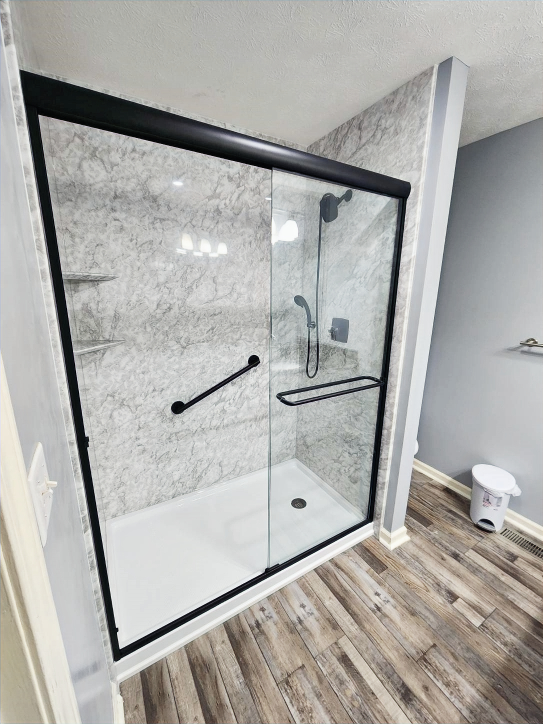 Bath Envy acrylic shower walls with a white base and black-framed glass enclosure